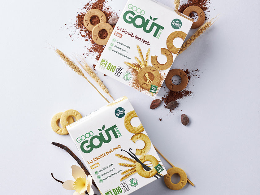 Deux boîtes de biscuits biologiques "Good Goût" avec des biscuits en forme d'anneaux, entourées de grains de café, fleurs de vanille et épis de blé, sur un fond blanc