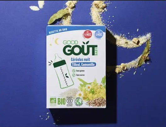Boîte de céréales bio pour bébé de la marque "Good Goût", saveur nuit (tilleul, camomille), posée sur un fond bleu foncé avec des céréales et fleurs séchées dispersées autour.