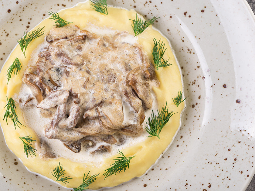 Assiette de boeuf Stroganoff avec de la purée de pommes de terre garnie de champignons à la crème.